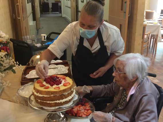 Cookridge Court Care Home resident Gwen Hancock, 96, helps decorate the cake with chef Lindsay Thewliss.