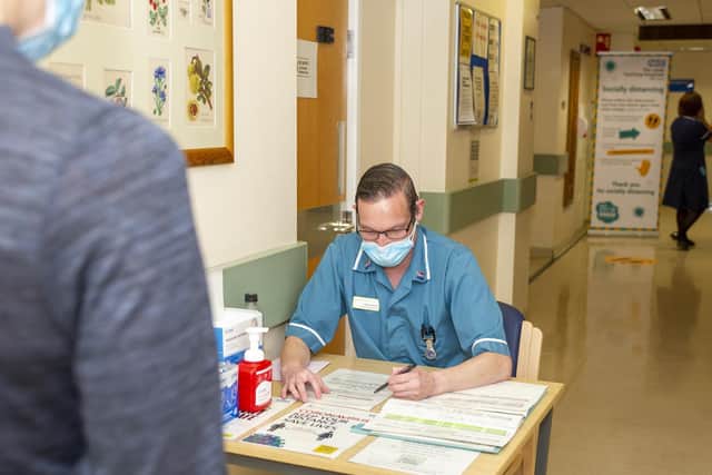Clinical suppoprt worker Richard Smith surveys visitors as they enter the outpatients department