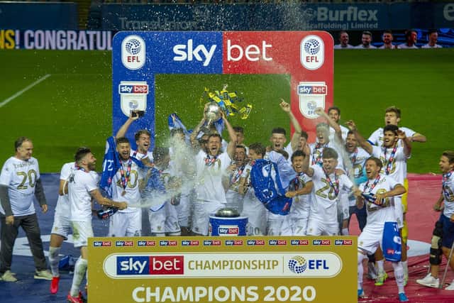 FINALLY! Stuart Dallas and Barry Douglas spray the bubbly while head coach Marcelo Bielsa, left, smiles looking on as Leeds United captain Liam Cooper lifts the Championship champions trophy. Picture by Tony Johnson.