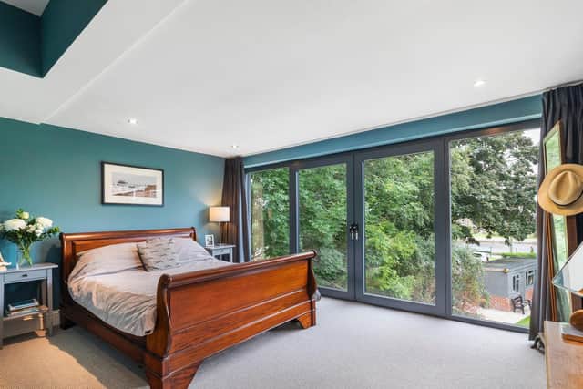 The bedroom in the new extension with glazed doors overlooking the garden and river beyond