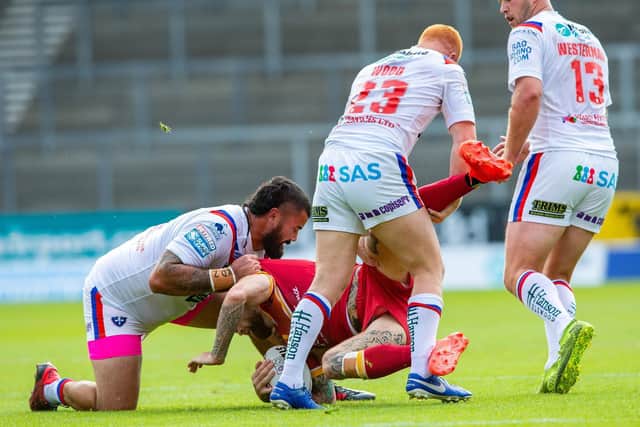 Sam Tomkins is tackled by Trinity's Dave Fifita, left and Josh Wood as Joe Westerman looks on. Picture by Bruce Rollinson.