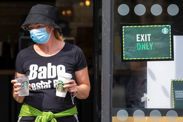A woman wearing a face mask leaves Starbucks.