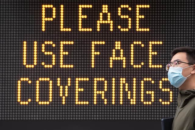 File photo of a man wearing a protective face mask walking past signage advising the use of face coverings.