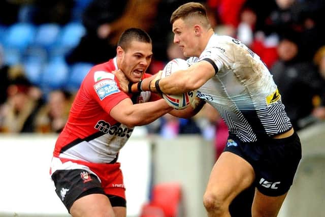 Ash Handley holds off Salford Red Devils playmaker Tui Lolohea. Picture: Steve Riding.