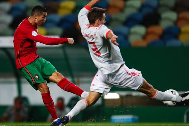 KEPT AT BAY: Leeds United's Diego Llorente flies into an attempted block as Portugal superstar Cristiano Ronaldo unleashes a shot in Wednesday night's friendly in Lisbon. Photo by CARLOS COSTA/AFP via Getty Images.