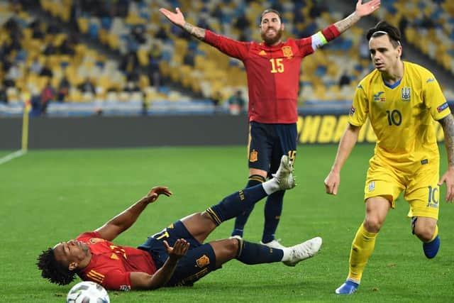 HANDFUL: Adama Traore is bundled to the floor as Spain captain Sergio Ramos appeals behind. Photo by SERGEI SUPINSKY/AFP via Getty Images.