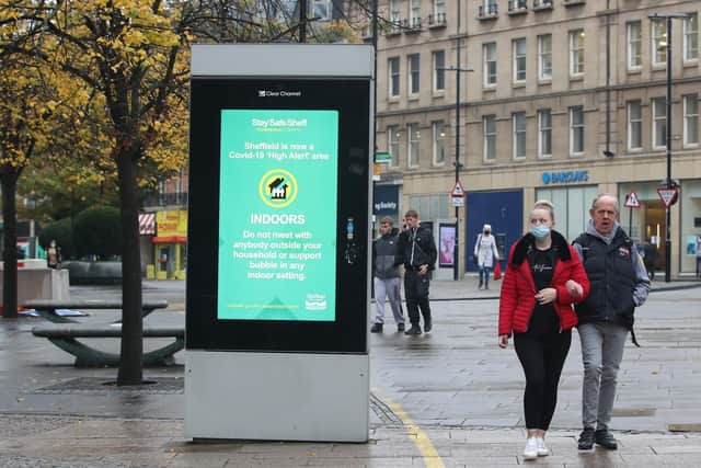 A woman wearing a face mask passes a coronavirus advice sign in Sheffield, as South Yorkshire is the latest region to be placed into Tier 3 coronavirus restrictions, which will come into effect on Saturday. Photo: PA