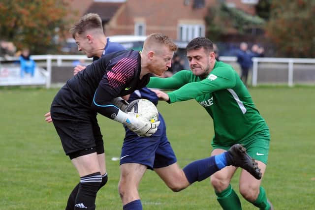 Whitkirk goalkeeper Paul Diamond collects under pressure from Adam Simpso,n of Hunslet, and his own defender Callum Brown. Picture: Steve Riding.
