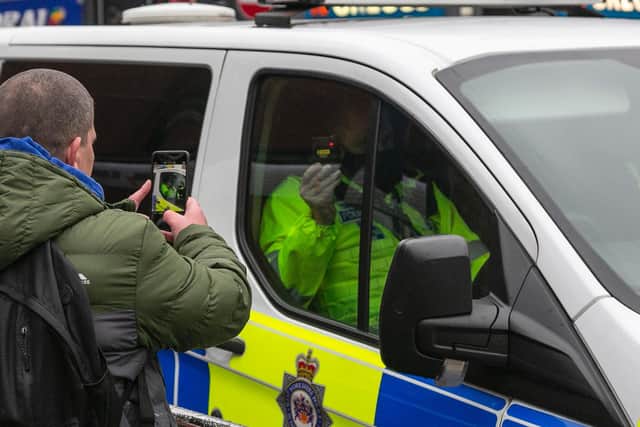 A man taking a photo of a police officer during an anti-lockdown protest in Leeds. SWNS.