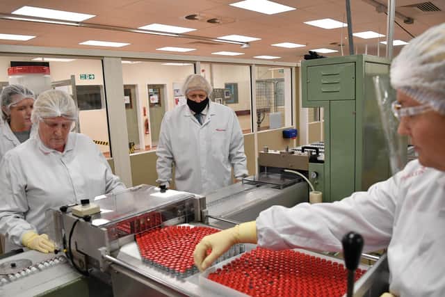 Prime Minister Boris Johnson (centre) watches workers perform quality testing during the 'fill and finish' stage of the manufacturing process of Covid-19 vaccines (Image: PA Wire/Paul Ellis)