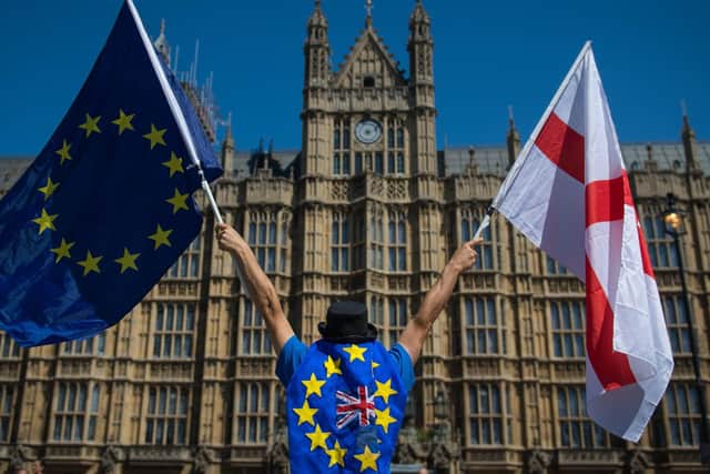 File photo dated 25/06/18 of an anti-Brexit demonstrator holding European Union and England flags outside the Houses of Parliament, in central London. The UK and EU have reached a post-Brexit trade agreement (photo: PA).