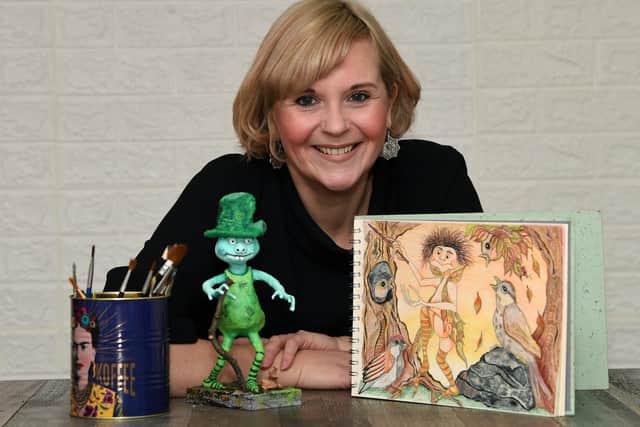 Angela Callard with her illustration for the front cover of her children's book ''The Truth about Itty Bitties' and a model, of an Itty Bitty.