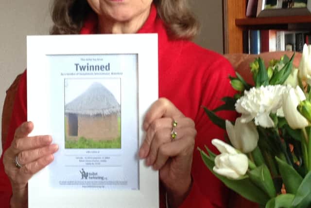 Soroptimist Judith Alce with a certificate showing the toilet she sponsored in Katete in the Eastern Province of Zambia.