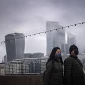 File photo  of a couple wearing face masks walking past a view of the City of London.