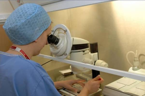 An embryologist working at the Seacroft fertility clinic checking eggs and embryos under a microscope.