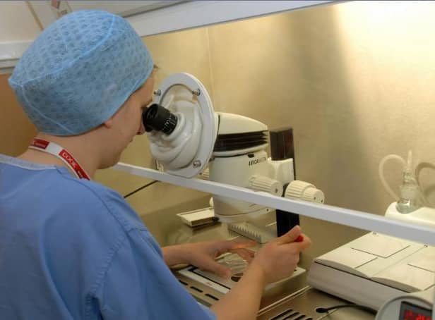 An embryologist working at the Seacroft fertility clinic checking eggs and embryos under a microscope.