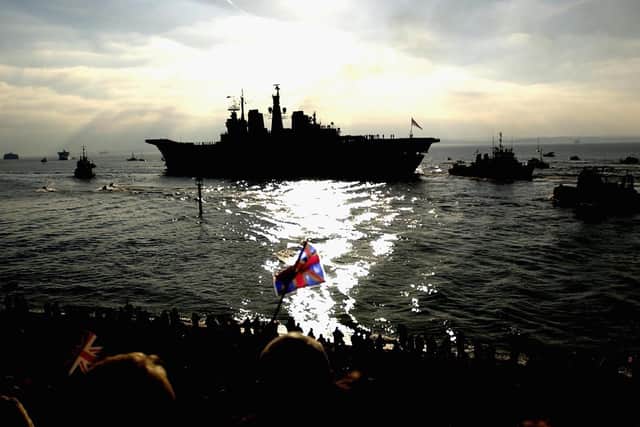 PORTSMOUTH, ENGLAND - Members of the public line the shore as the aircraft carrier HMS Ark Royal leaves her base in Portsmouth to lead a Naval Task Group to the Mediterranean. (Photo by Julian Herbert/Getty Images)