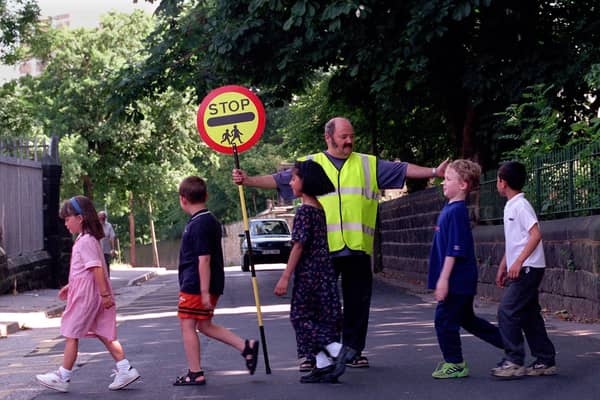 School crossing patrol officer Stuart Smith helps pupils at Christ Church Co of E School get across the road safely in July 1999.