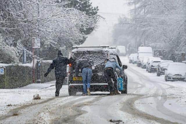 An amber National Highways warning for snow is in place across Yorkshire. A group of people push a car through the snow in Farsley in 2021.