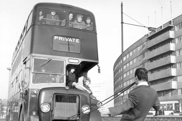 A circus publicity stunt shows a member of Billy Smart's circus pulling a Leeds City Transport bus full of passengers, with his teeth in January 1965. Quarry Hill flats can be seen in the background. PIC: West Yorkshire Archive Service