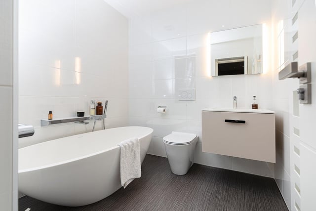 This sleek bathroom features a slipper bath and a wash basin with vanity unit surround.