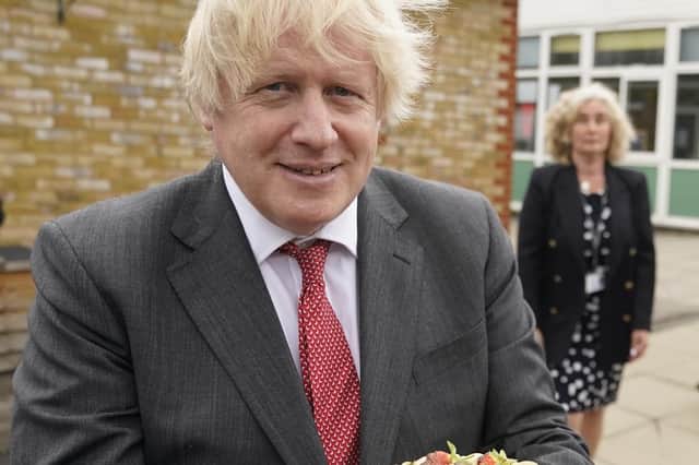 In this Downing Street handout photograph dated 19/6/2020 Boris Johnson holds up a birthday cake - baked for him by school staff - during a visit to Bovingdon Primary Academy.