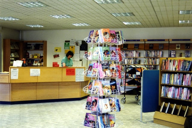 Inside Swinnow Library on Swinnow Lane. This branch opened in 1987 to replace the previous library based in Swinnow School on Swinnow Road. A paperback stand is seen in the foreground and the counter is on the left.