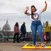 Members of the public watch actor Jacqueline Jossa as she walks barefoot over a brick path made up of 30,000 LEGO pieces at Observation Point in London to raise funds for Comic Relief's Red Nose Day 2022. Photo: PA