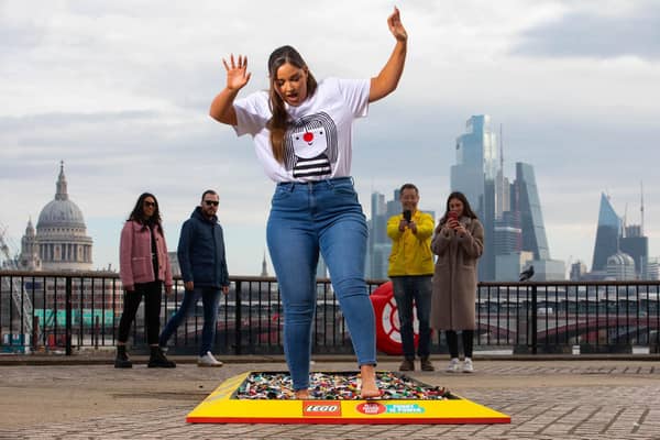 Members of the public watch actor Jacqueline Jossa as she walks barefoot over a brick path made up of 30,000 LEGO pieces at Observation Point in London to raise funds for Comic Relief's Red Nose Day 2022. Photo: PA