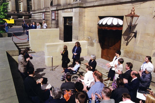 A crowd is gathered outside the Municipal Buildings on The Headrow for the opening of the new ramp providing level access to the Central Library and City Museum in May 1993. The entrance to Stumps public house, also benefitting from the ramp, can be seen on the right, with Calverley Street visible on the left.