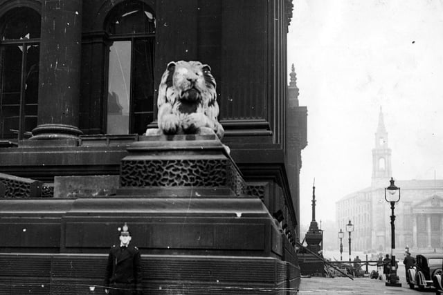 The front of the Town Hall, along Calverley Street. A policeman stands to the left, dwarfed by one of Keyworth's lions. To the right, barriers surround the bomb damaged area, roughly where the Calverley Street entrance is. The Civic Hall is visible in the background.