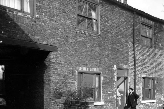 Kingston Place in March 1965. On the left is a passageway which led to the back of numbers 3 to 8. Number 1 was built at an angle to the other houses in the row. A woman is in the doorway talking to a man in uniform.