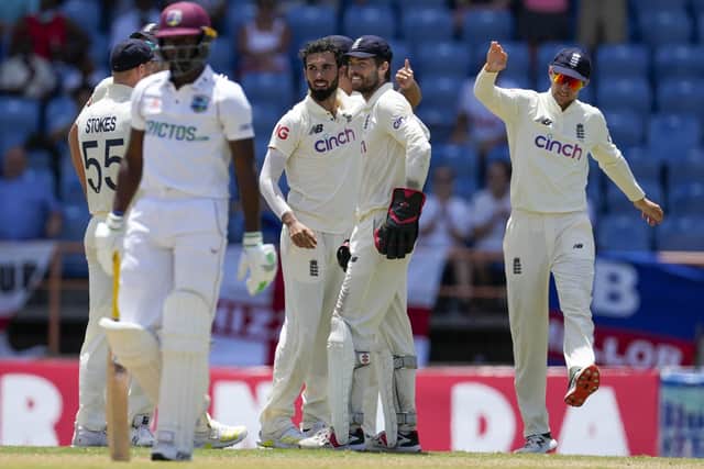 England's Saqib Mahmood celebrates with Chris Woakes and Joe Root the dismissal of West Indies' Shamarh Brooks during day two of their third Test cricket match at the National Cricket Stadium in St. George, Grenada, Friday, March 25, 2022. (AP Photo/Ricardo Mazalan)