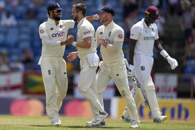 England's Chris Woakes, center, celebrates with teammates Saqib Mahmood, left, and Ben Stokes the dismissal for no runs of West Indies' Jason Holder, back right, during day two of their third Test cricket match at the National Cricket Stadium in St. George, Grenada, Friday, March 25, 2022. (AP Photo/Ricardo Mazalan)