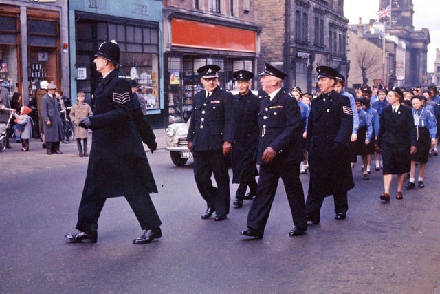The procession rounds the corner from Queen Street into Wesley Street, by Boots the Chemist and the private Silver Library. At this point it is members of the police force and of the Girl Guides that are making up this contingent. Besides regular police there are some special constables including Arthur Nunns, a local painter and decorator. The guides are also well represented.
