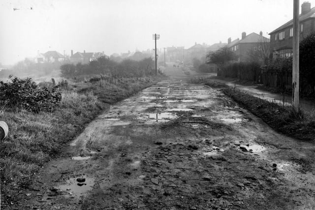 Looking East along Primley Park Lane towards Harrogate Road in October 1954.. Muddy road with people and a car in the distance.