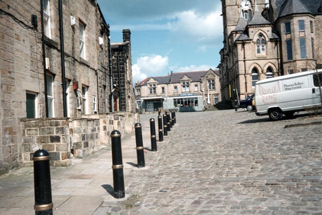 Yeadon's Devonshire Place, used as a car park. Shops on the left front onto the High Street. This is looking across the Town Hall Square, with Yeadon Town Hall to the right. The building in the centre is Yeadon library in what was formerly a branch of Leeds Industrial Co-operative Society - Co-op grocers.