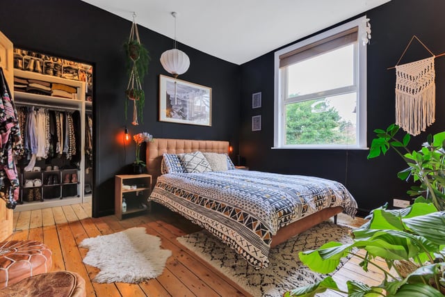 There are two bedrooms on the first floor of the property. This master bedroom is painted in a similar black to the living room, with the owners adding in plenty of foliage, textured rugs and wood tones to the room.