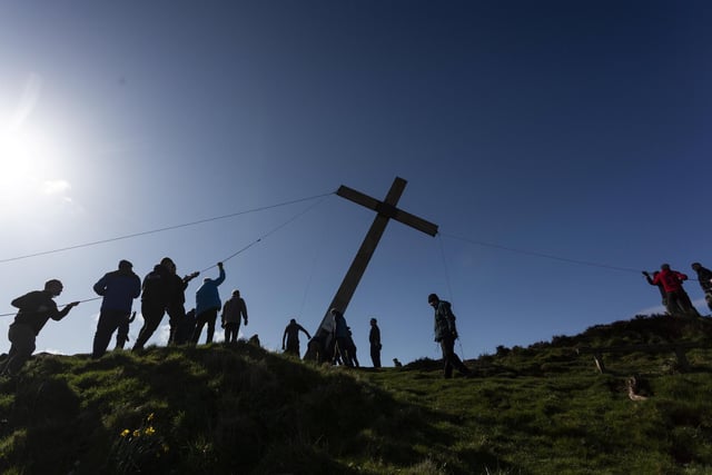 Once carried to the summit, the volunteers pull the cross into place