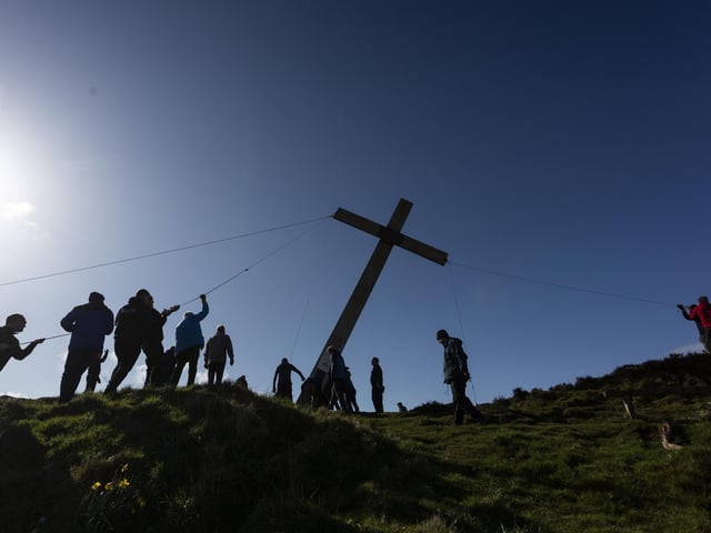 Once carried to the summit, the volunteers pull the cross into place
