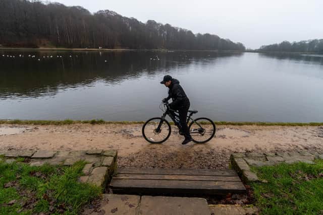 Members of the public enjoying a walk around Roundhay Park, Leeds. Pictured A man exercises on his bike around Waterloo Lake. Photo: James Hardisty