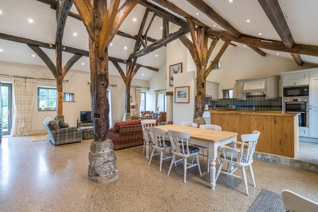 Dining space, kitchen, and living room all merge seamlessly within the open design of The Aisled Barn's interior.