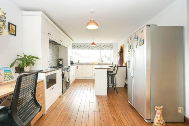 The kitchen is sleek, white, and modern with plenty of room for a large fridge freezer.