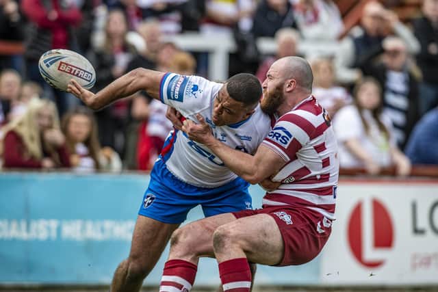 Reece Lyne offloads out of a tackle by Wigan's Jake Bibby. Picture by Tony Johnson.