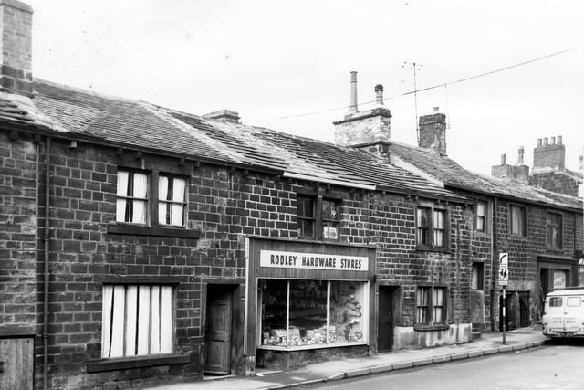 Stone buildings on Town Street in February 1965 which had originally been built to house navvies working on the Leeds and Liverpool Canal. Rodley Hardware Stores is in view with tools, pans and wrought iron plant holders among the many things on display.