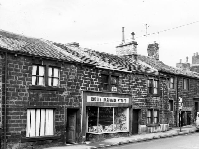 Stone buildings on Town Street in February 1965 which had originally been built to house navvies working on the Leeds and Liverpool Canal. Rodley Hardware Stores is in view with tools, pans and wrought iron plant holders among the many things on display.