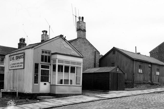 Three different wooden buildings on Wesley Terrace pictured in March 1965. On the left is the premises of Glenwell Equipment, electrical engineers specialising in 'Automatic Control Panels and Electric Air Heater Units'. In the centre is a garage with a sign above the door asking people not to park outside. On the right is a larger wooden hut which had been the meeting place for the Mutual Club. It provided a place where the men of Rodley could meet to play billiards, chess or draughts.