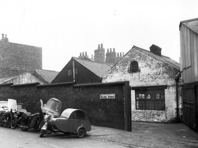 Garages and warehouses on Manor Street pictured in February 1961. Several motorbikes with sidecars are parked towards the left.