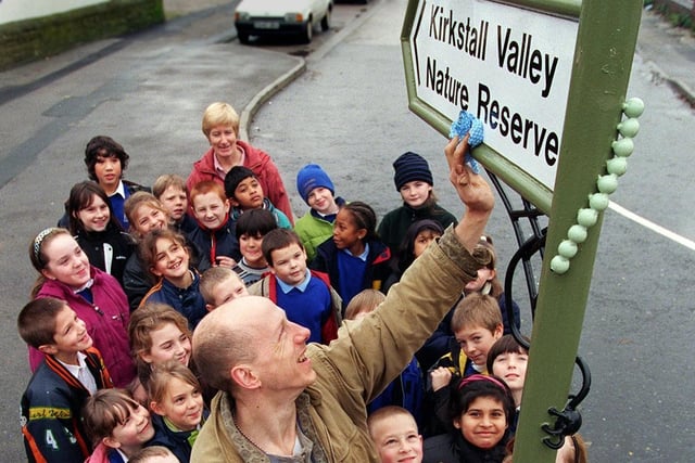 Sculptor Mick Kirkby Geddes puts the finishing touches to a new road sign to Kirkstall Valley Nature Reserve in November 1998. He is watched by pupils from from Burley St. Matthias School who helped create it.