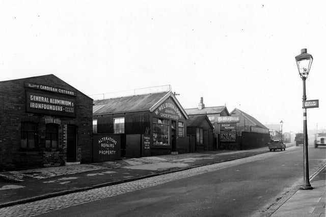 The west side of Cardigan Road in January 1954. These buildings house a number of businesses. 'Pickles Bros. (slaters) Ltd', 'S. Huggard & Son, plumbers, 'W. Welborn & Son, joiners & undertakers and 'H.J. Gill & Co. (Leeds) Ltd, cistern makers.